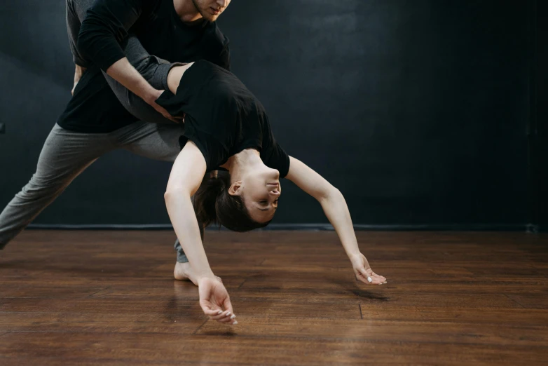 a man and a woman doing a handstand on a wooden floor, by Arabella Rankin, arabesque, sydney hanson, low quality photo, thumbnail, full - body artwork