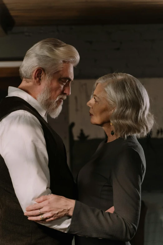 a man and a woman standing next to each other, photorealism, silver hair and beard, [ theatrical ], cinema still, profile image