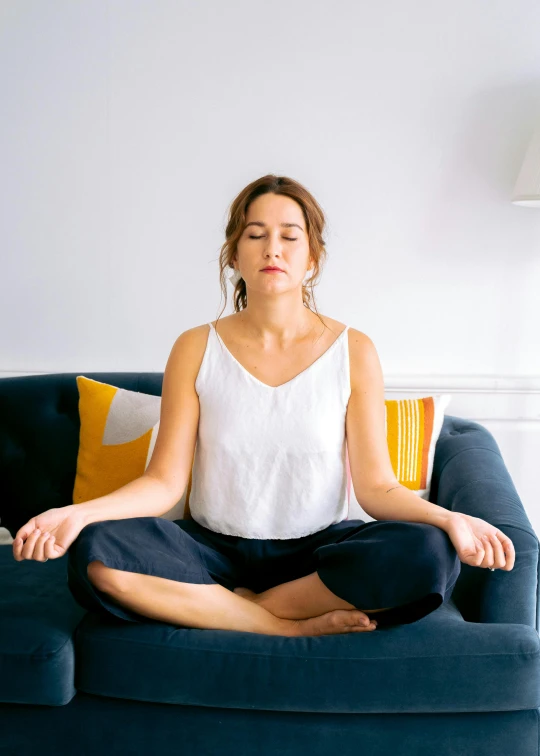 a woman sitting on top of a blue couch, meditation pose, pointé pose;pursed lips, during the day, halations