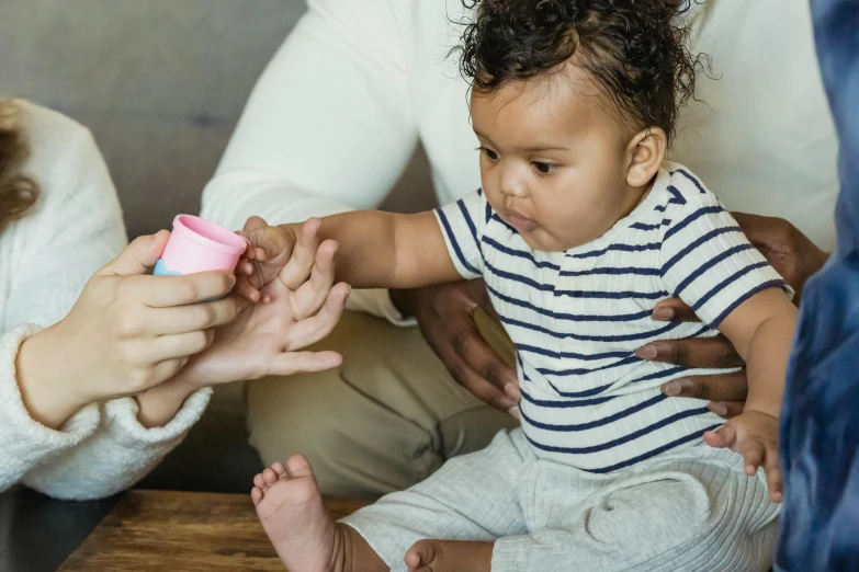 a close up of a person holding a baby, pestle, holding paws, holding a bottle, boy with neutral face