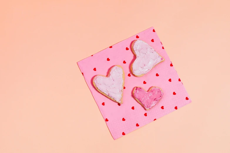 a couple of heart shaped cookies sitting on top of a pink piece of paper, trending on pexels, background image, thumbnail, 3 1, various posed