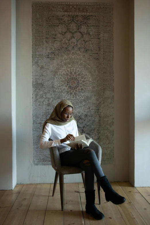 a woman sitting in a chair reading a book, hurufiyya, jemal shabazz, wall art, student, grey