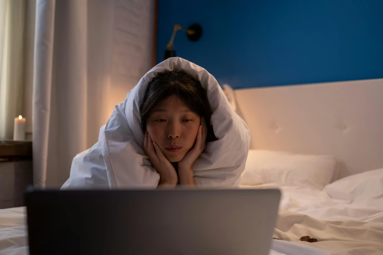 a woman laying in bed with a laptop, a cartoon, trending on pexels, cloak covering face, asian descent, scene from live action movie, ignant