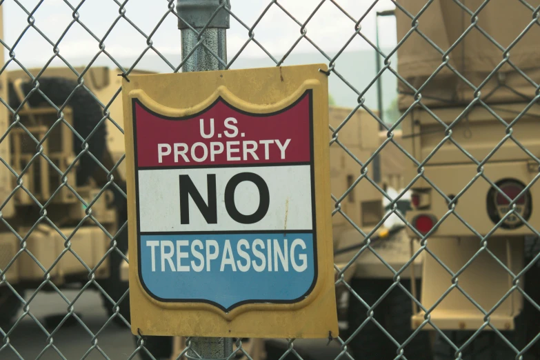a no trespassing sign on a chain link fence, by Bernie D’Andrea, unsplash, graffiti, military vehicles, square, 4k still, usa