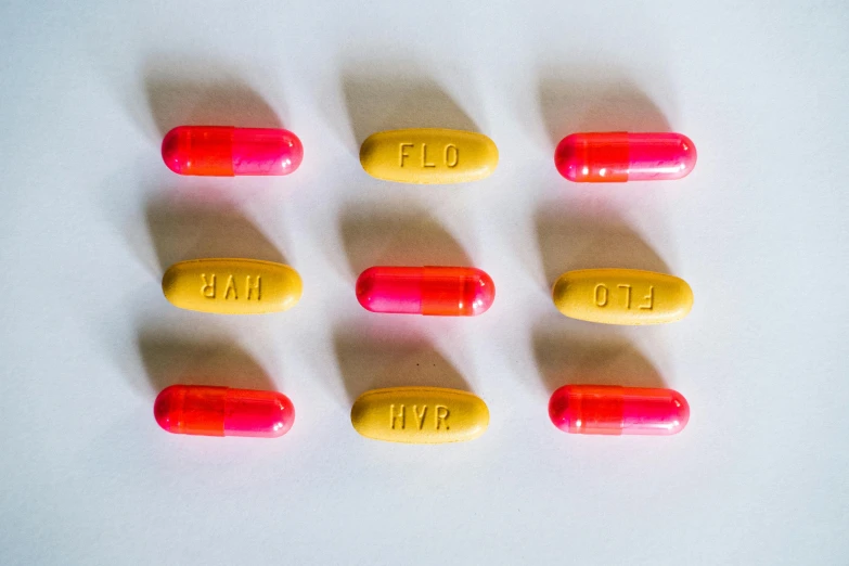 a group of pills sitting on top of a white surface, by Jessie Algie, antipodeans, pink and yellow, yellow and red, shot on sony a 7, replicas