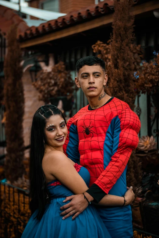 a woman in a blue dress standing next to a man in a spider - man costume, pexels contest winner, latino american, 18 years old, lovely couple, el chavo