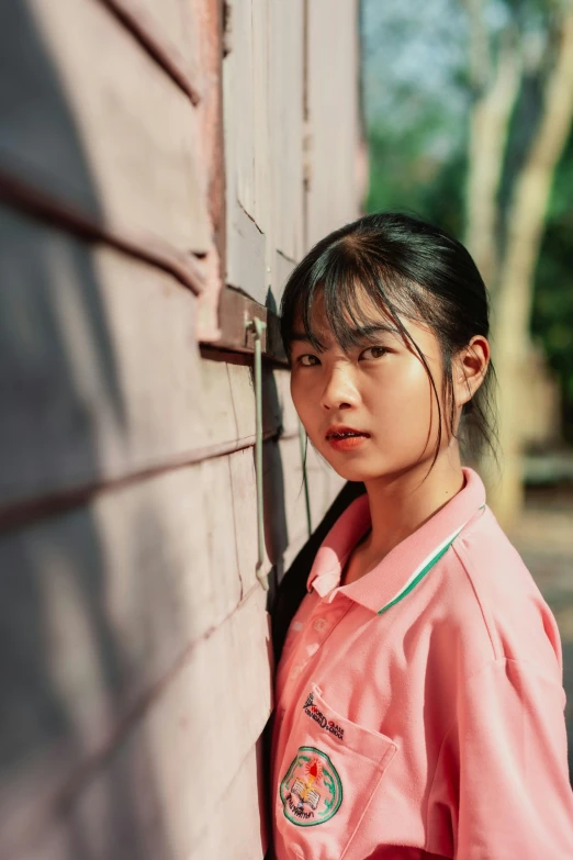 a girl in a pink shirt leaning against a wall, inspired by Ma Yuanyu, pexels contest winner, photorealism, asian face, film color photography, 18 years old, mai anh tran