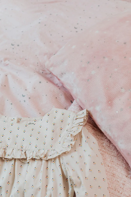 a close up of a baby's dress on a bed, by Lucia Peka, trending on unsplash, baroque, with stars, pink fur, soft surface texture, instagram story