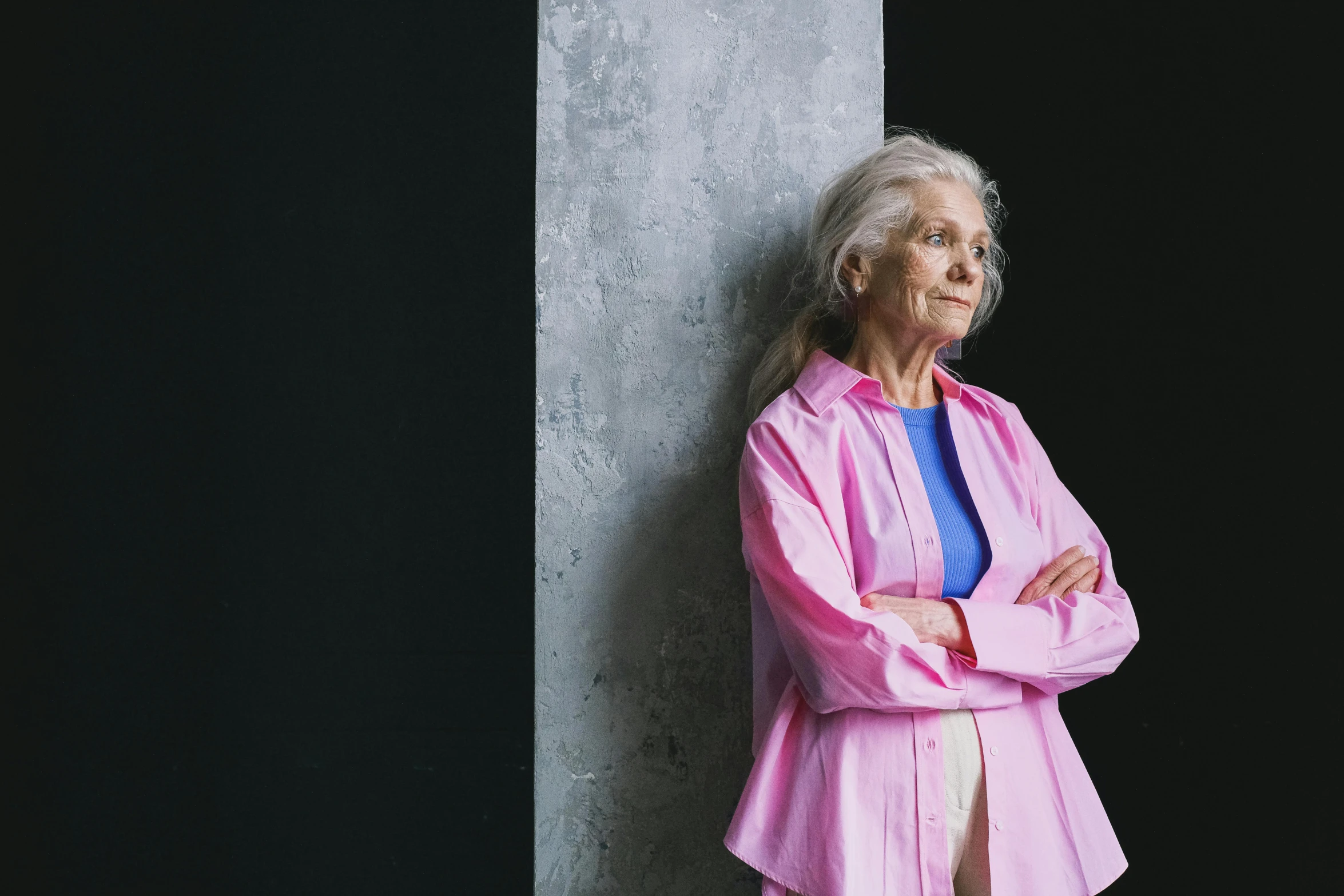 a woman leaning against a wall with her arms crossed, inspired by Louise Bourgeois, pexels contest winner, hyperrealism, pink clothes, elderly, engineer, looking straight