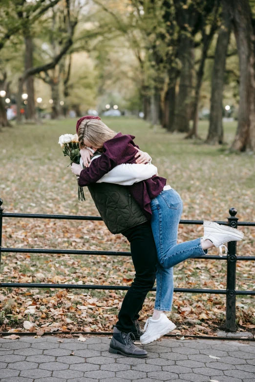 a man giving a woman a hug in a park, sydney sweeney, carrying flowers, fall season, 🚿🗝📝