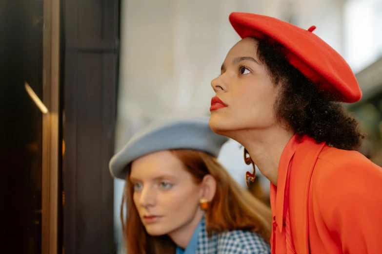 two women standing next to each other in front of a mirror, trending on pexels, renaissance, red hat, inspired in balthus, berets, red orange blue beige