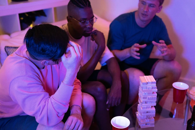 a group of people sitting on top of a couch, by Benjamin Block, pexels contest winner, jenga tower, purple and pink and blue neons, poker, queer