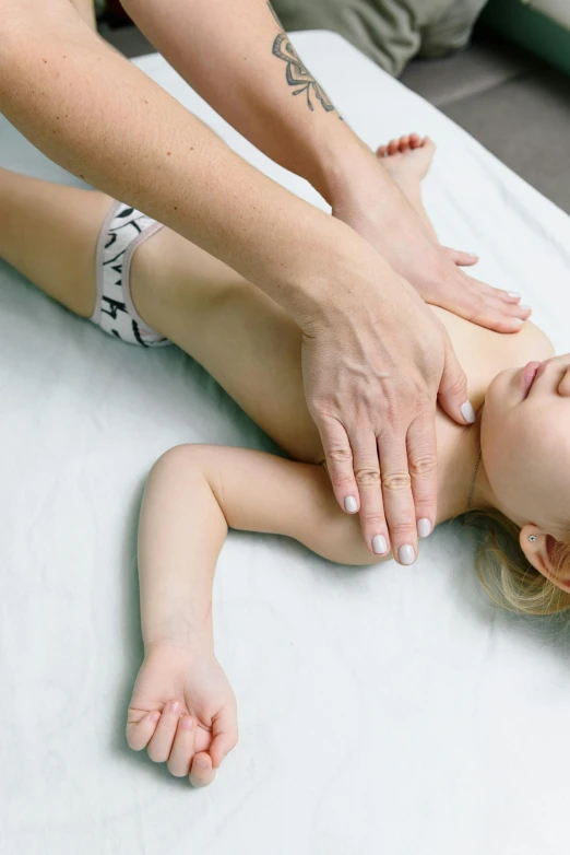 a woman is giving a child a massage, a picture, top half of body, full shot photograph, thumbnail, luca