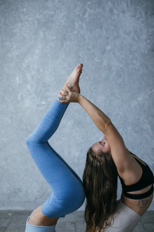a woman doing a yoga pose on the floor, by Jessie Algie, unsplash, arabesque, woman holding another woman, blue and grey, studio shoot, upper body image