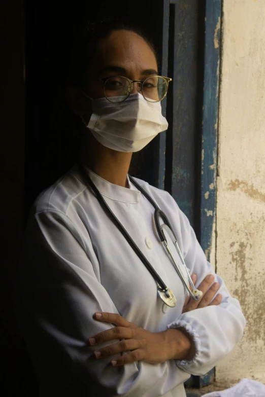 a woman with a stethoscope standing in front of a window, pexels, egypt, finely masked, wearing lab coat and glasses, standing in an alleyway