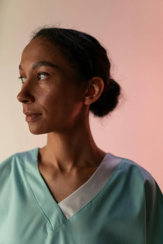 a woman standing in front of a pink wall, hyperrealism, surgical gown and scrubs on, low key light, ashteroth, pictured from the shoulders up