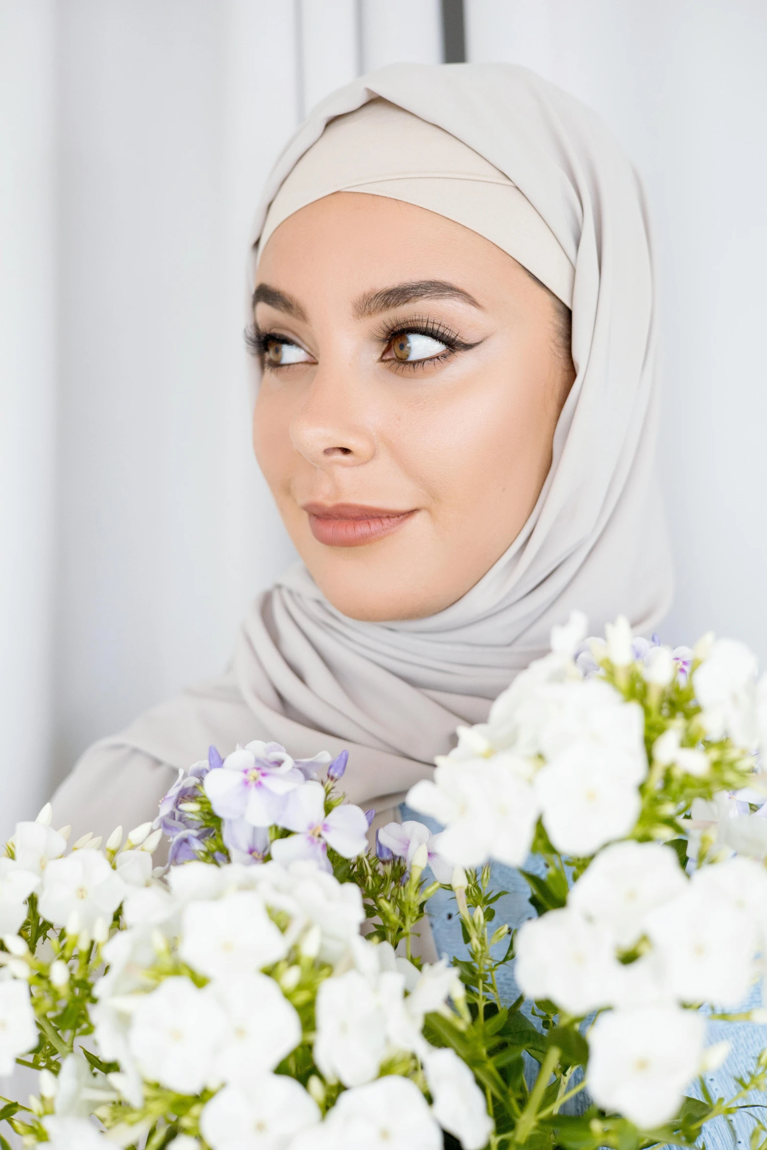 a woman in a hijab holding a bouquet of flowers, silver and muted colors, photoshoot for skincare brand, day time, tanned ameera al taweel