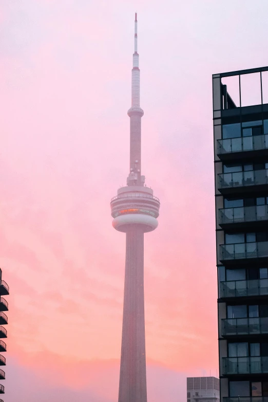 a tall tower sitting in the middle of a city, by Carey Morris, pexels contest winner, boards of canada album cover, the sky is pink, morning detail, promo image