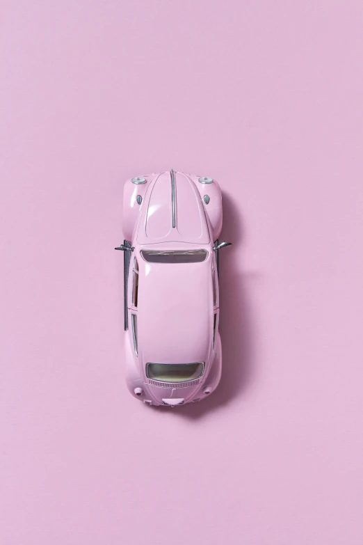 a toy car sitting on top of a pink surface, inspired by Otto Eckmann, trending on unsplash, patricia piccinini, beetle, overhead view, ilustration