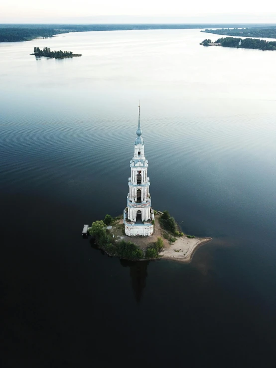 a small island in the middle of a large body of water, inspired by Konstantin Vasilyev, pexels contest winner, lead - covered spire, drone photo, with a white, documentary still