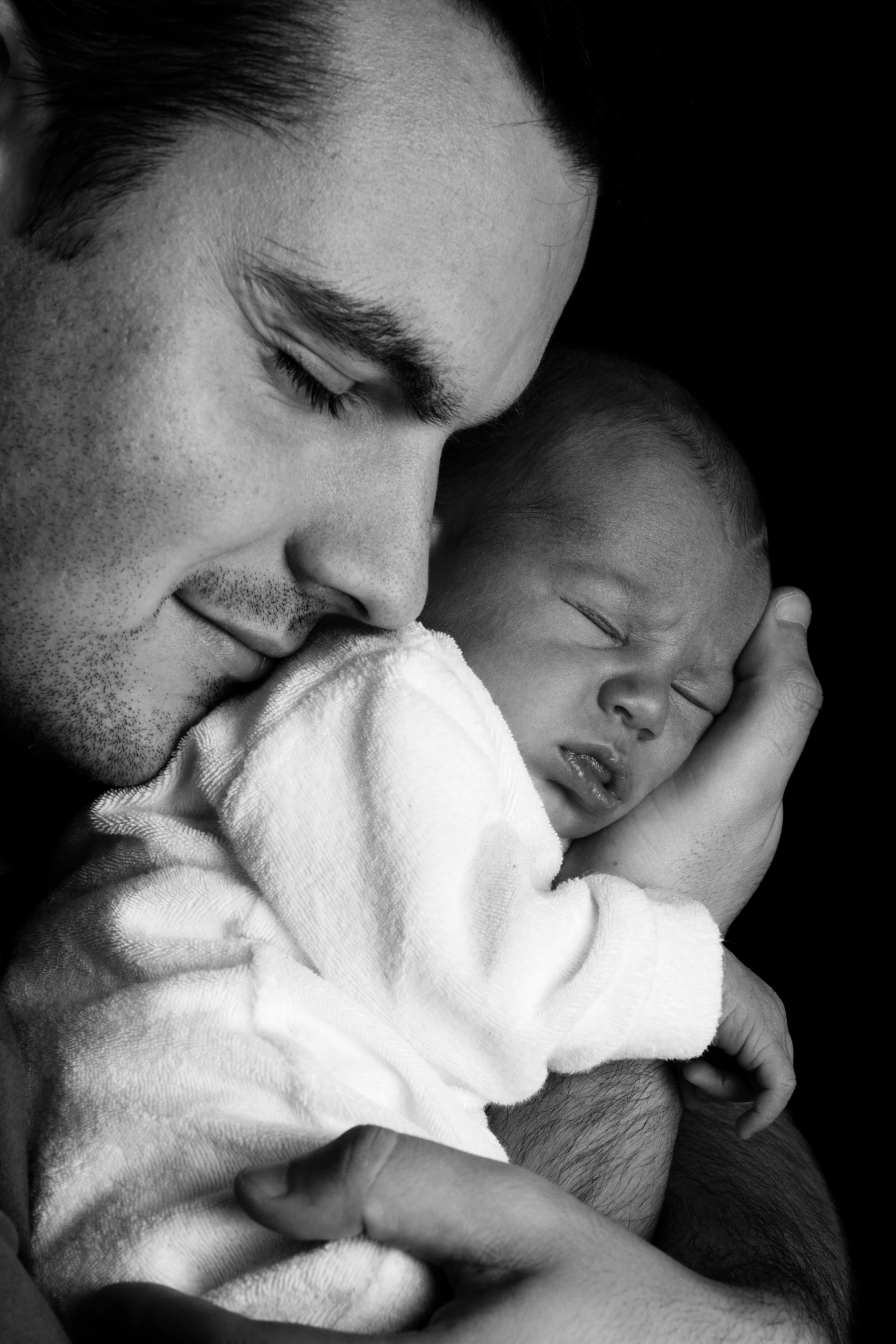 a man holding a baby in his arms, a black and white photo, by Matt Stewart, flickr, photo of a beautiful, asleep, istockphoto, bowater charlie and brom gerald