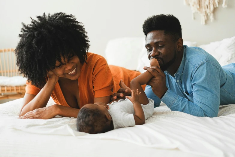 a man and woman laying on a bed with a baby, pexels contest winner, ebony, profile image, proud looking, high resolution