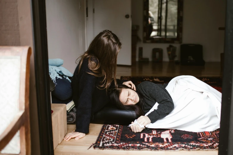 a woman laying on the floor next to another woman, unsplash, hurufiyya, acupuncture treatment, covered with blanket, profile image, with furniture overturned