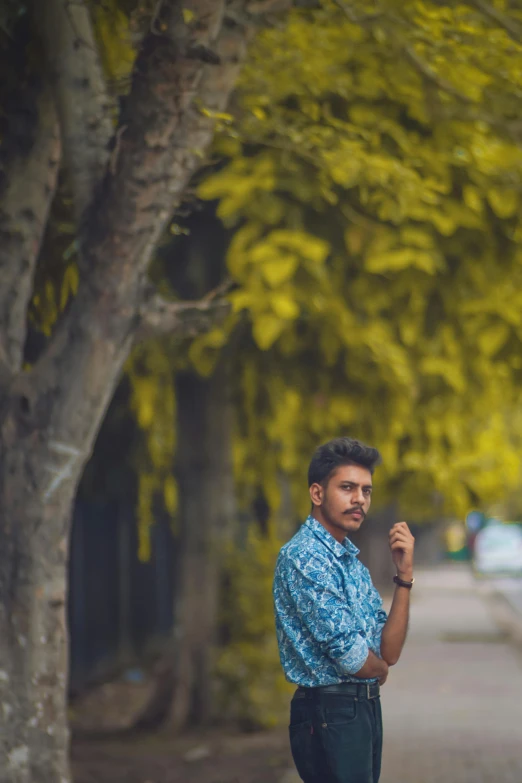 a man standing in the middle of a tree lined street, by Max Dauthendey, pexels contest winner, thoughtful pose, yellow and green, jayison devadas, ((portrait))