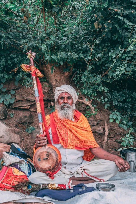 a group of men sitting next to each other, an album cover, pexels contest winner, samikshavad, holding a spear, portrait photo of an old man, lush surroundings, instrument