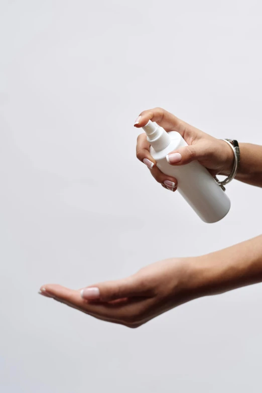 a person holding a bottle of hand sanitizer, by Gavin Hamilton, on grey background, spray, profile image, skincare