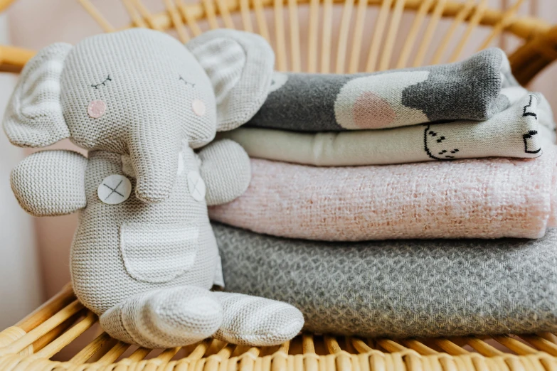 a stack of blankets sitting on top of a wicker chair, by Emma Andijewska, trending on pexels, cute elephant, toys, grey clothes, made of fabric