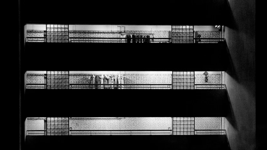 a black and white photo of an escalator, a black and white photo, inspired by Andreas Gursky, bauhaus, group of people in a dark room, prison bars, triptych, nighttime scene