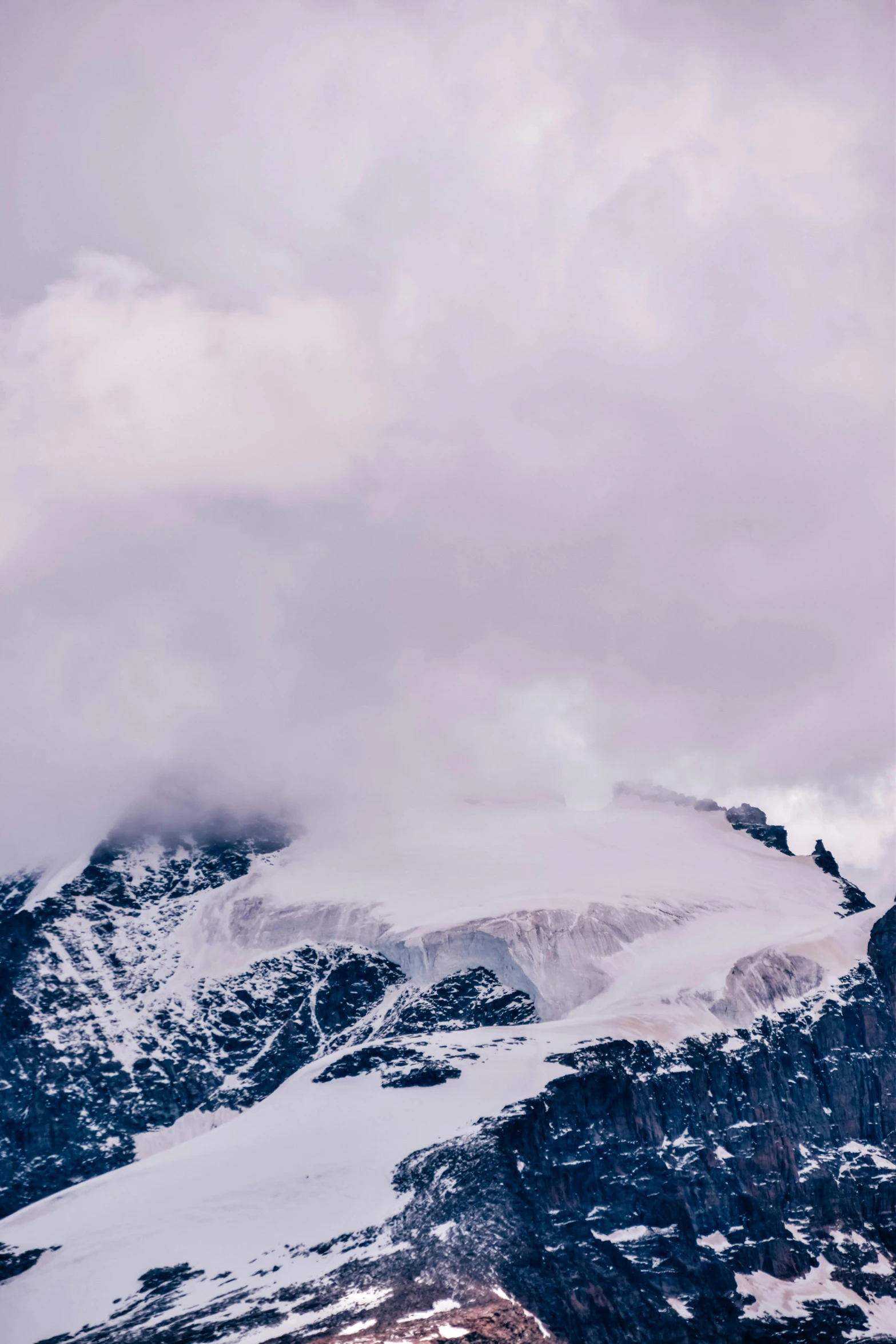 a man standing on top of a snow covered mountain, an album cover, trending on unsplash, minimalism, swiss alps, low clouds after rain, glaciers, “ aerial view of a mountain