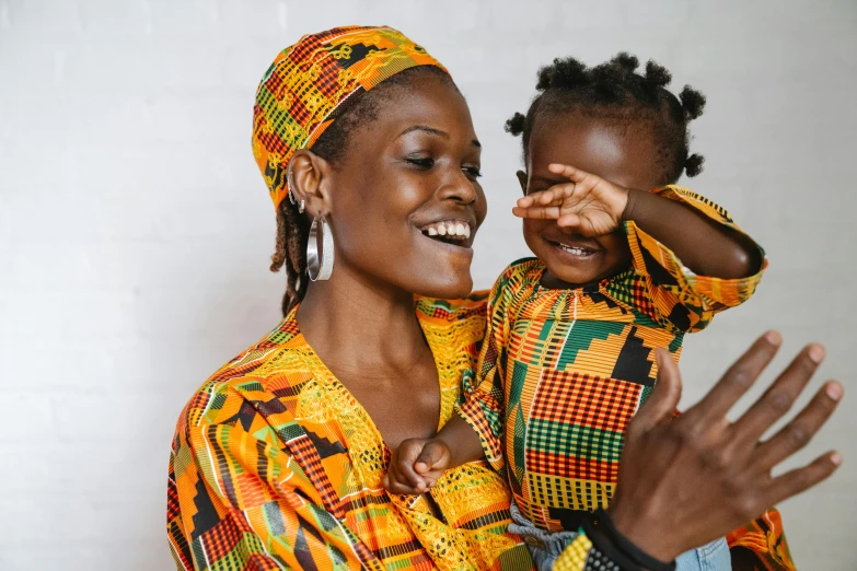 a woman holding a child in her arms, pexels contest winner, afrofuturism, colourful clothes, happy family, wearing traditional garb, avatar image