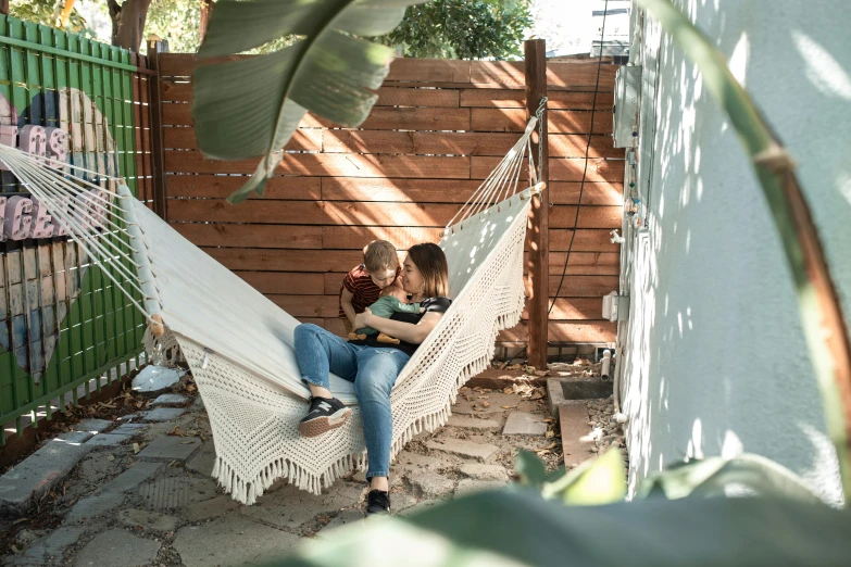 a couple of people that are sitting in a hammock, white block fence, justina blakeney, carefully crafted, profile image