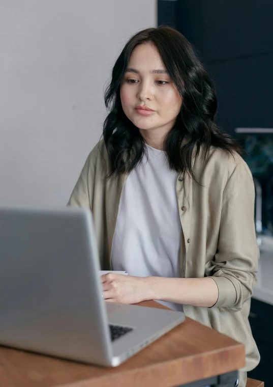 a woman sitting in front of a laptop computer, inspired by Li Di, trending on unsplash, wearing a light shirt, low quality photo, ethnicity : japanese, maintenance