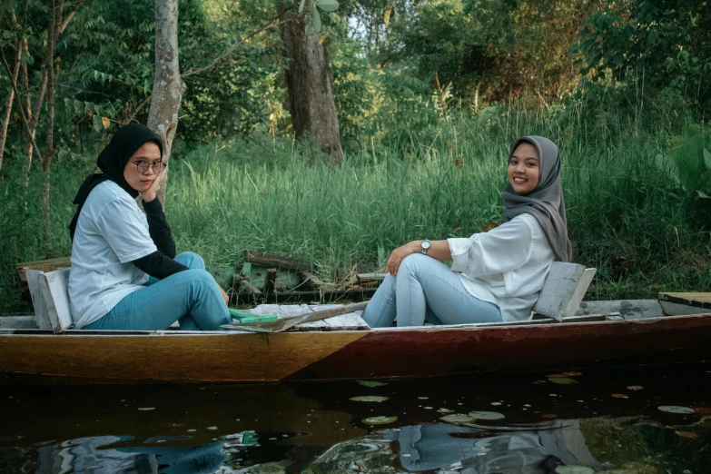 a couple of women sitting on top of a boat, by Basuki Abdullah, pexels contest winner, in front of a forest background, avatar image, student, waterway