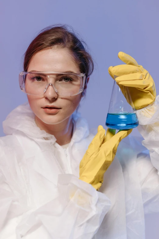 a woman in a lab coat holding a flask, shutterstock, analytical art, yellow latex gloves, blue robes, gen z, wearing goggles