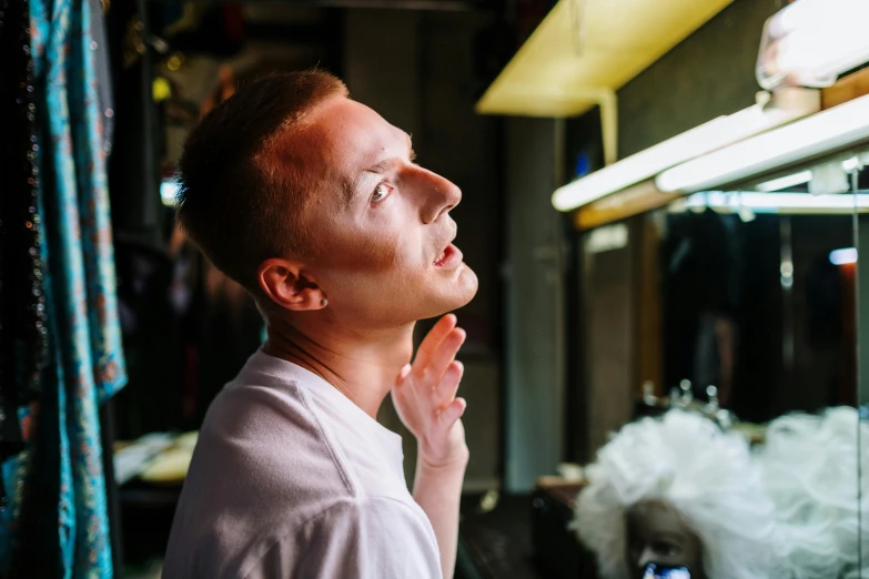 a man standing in front of a glass display case, by Julia Pishtar, pexels contest winner, hyperrealism, putting makeup on, singing at a opera house, with high cheekbones, morning lighting