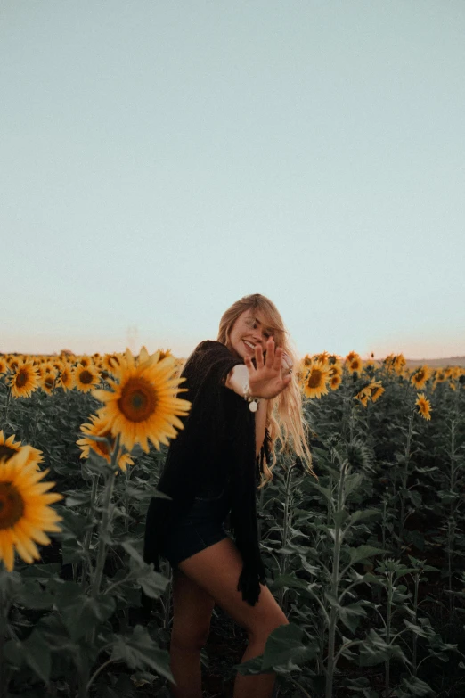 a woman standing in a field of sunflowers, pexels contest winner, flirting smiling, a blond, floating, low quality photo