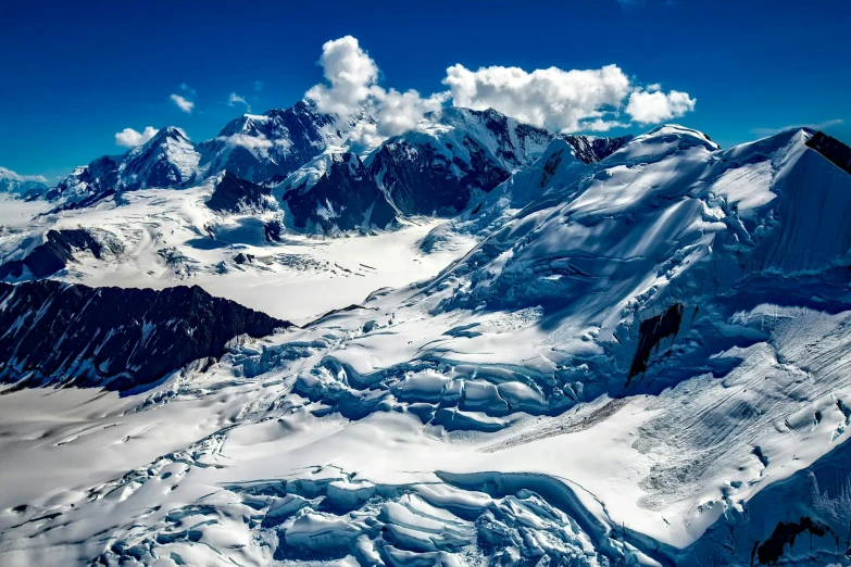 a group of people standing on top of a snow covered mountain, by Alison Geissler, pexels contest winner, visual art, “ aerial view of a mountain, glaciers and ice and snow, new zealand, alaska