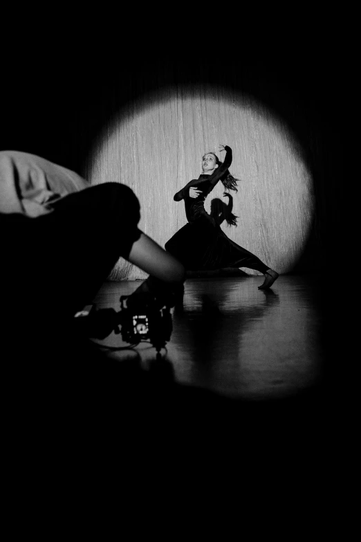 a couple of people sitting on top of a wooden floor, inspired by Jerry Schatzberg, film noir lighting, as though she is dancing, camera obscura, person in foreground