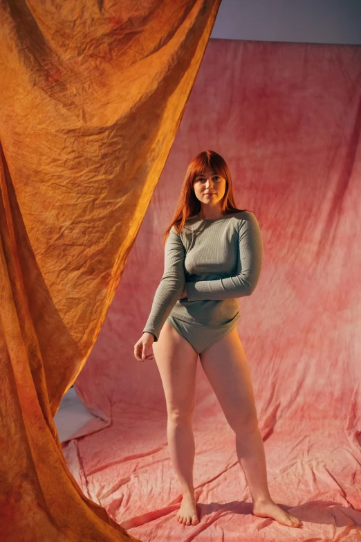 a woman standing in front of a curtain, an album cover, unsplash, renaissance, muted colored bodysuit, red head, plus-sized, mary elizabeth winstead