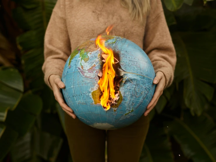 a woman holding a burning globe in her hands, an album cover, by Julia Pishtar, pexels contest winner, environmental art, graphic print, the earth sprouts lava, awkward situation, the born fire