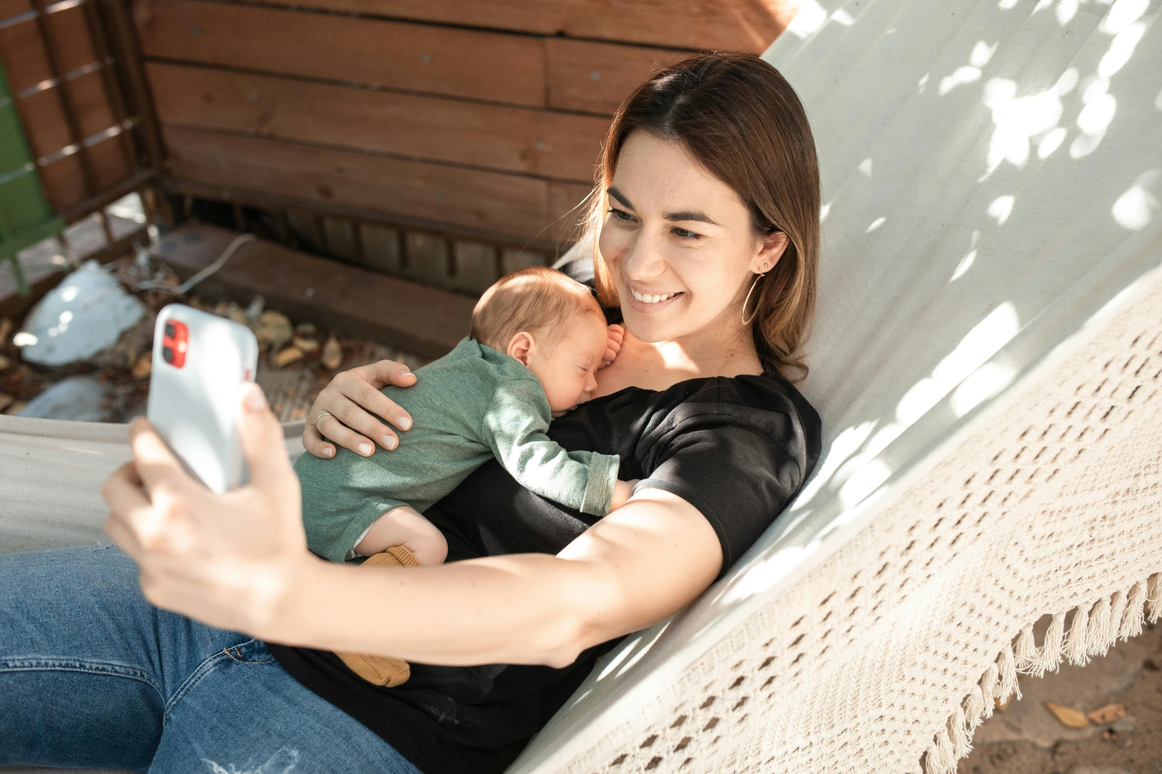 a woman sitting in a hammock holding a baby, a picture, pexels contest winner, happening, she is holding a smartphone, australian, close together, avatar image