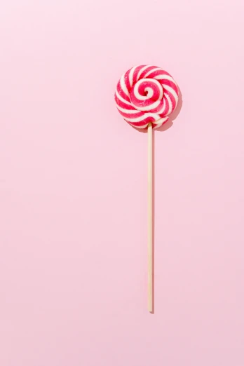 a pink lollipop on a stick against a pink background, by Adam Marczyński, unsplash, made out of sweets, striped, edible crypto, spiral