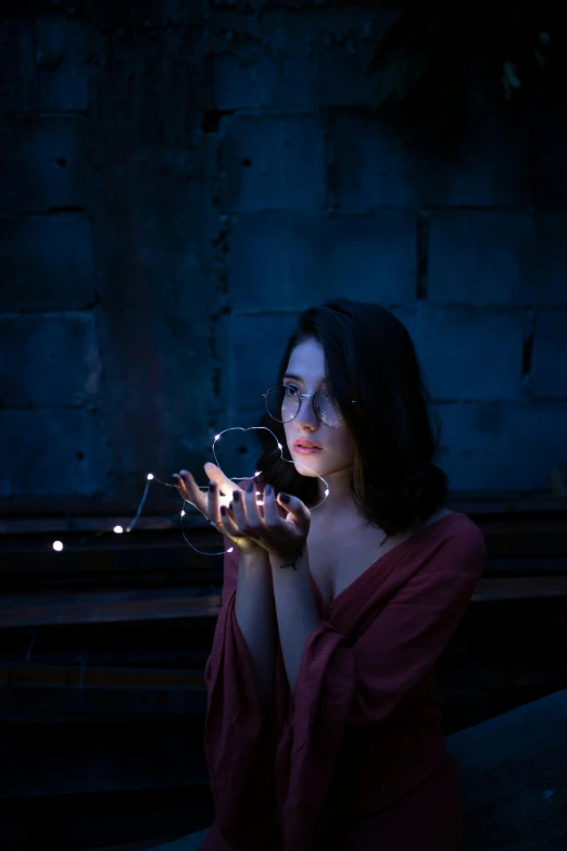 a woman holding a string of lights in her hands, a portrait, pexels contest winner, magical realism, contemplating, low quality photo, anna nikonova aka newmilky, light paint