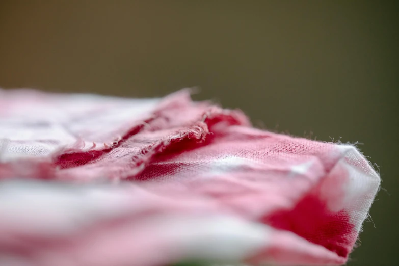 a close up of a piece of pink fabric, by Julian Allen, unsplash, process art, red and white, ragged clothes, carnation, injured