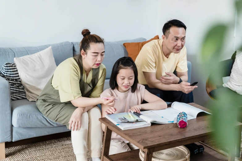 a family sitting on a couch looking at a magazine, pexels contest winner, mingei, board games on a table, avatar image, asian female, worried