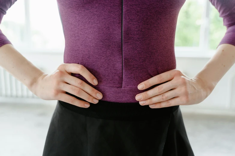 a woman standing with her hands on her hips, by Rachel Reckitt, trending on pexels, wearing purple undershirt, cysts, middle close up, spasms